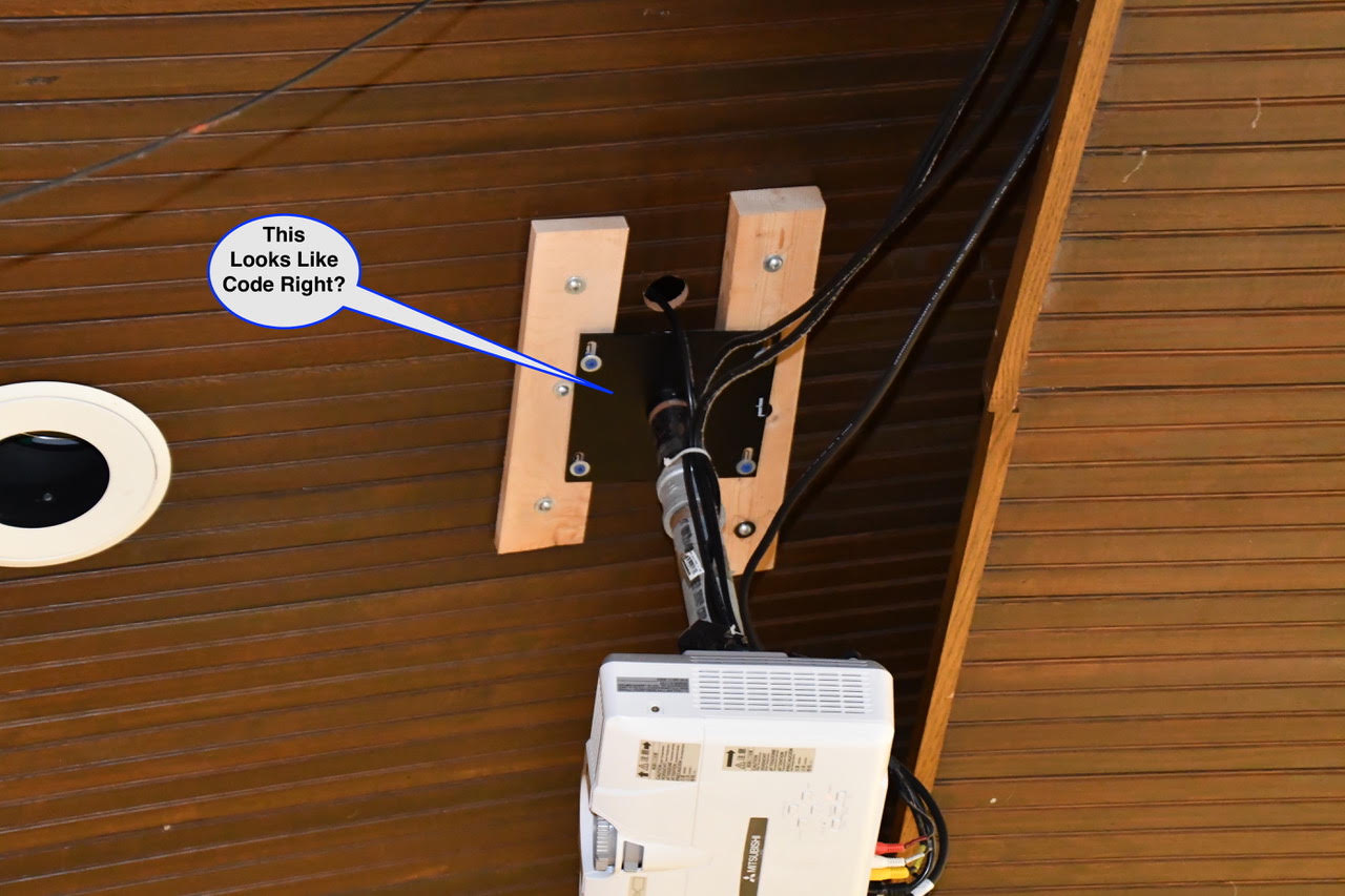 WOS August 3 Ceiling-mounted projector on wooden beams with several cables connected to it.