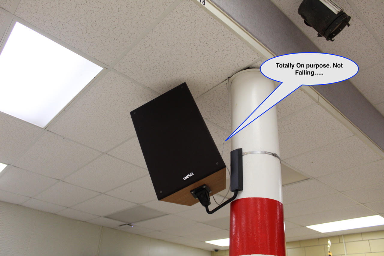 WOS August 7 Yamaha speaker mounted to a white pillar with a red band in an indoor room, plus a speech bubble reading 'Totally On purpose. Not Falling.....'